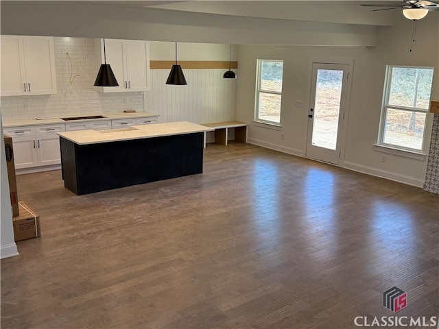 kitchen with white cabinetry, decorative light fixtures, black electric cooktop, a kitchen island, and decorative backsplash