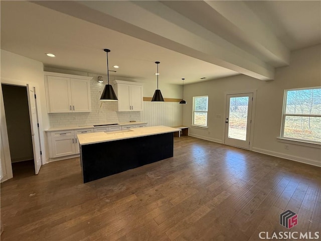 kitchen with hanging light fixtures, white cabinetry, a kitchen island, and decorative backsplash