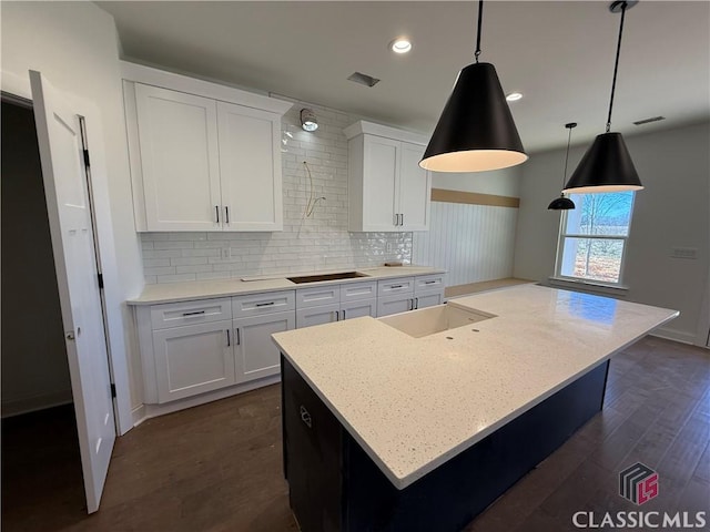 kitchen featuring tasteful backsplash, white cabinetry, black electric cooktop, and decorative light fixtures