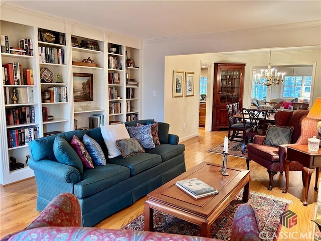 living room with a notable chandelier, light hardwood / wood-style floors, built in features, and crown molding