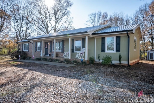 view of front of house featuring brick siding, a porch, a standing seam roof, metal roof, and an outdoor structure