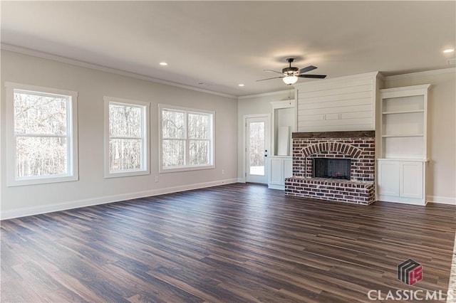 unfurnished living room with a brick fireplace, crown molding, dark wood-type flooring, and ceiling fan