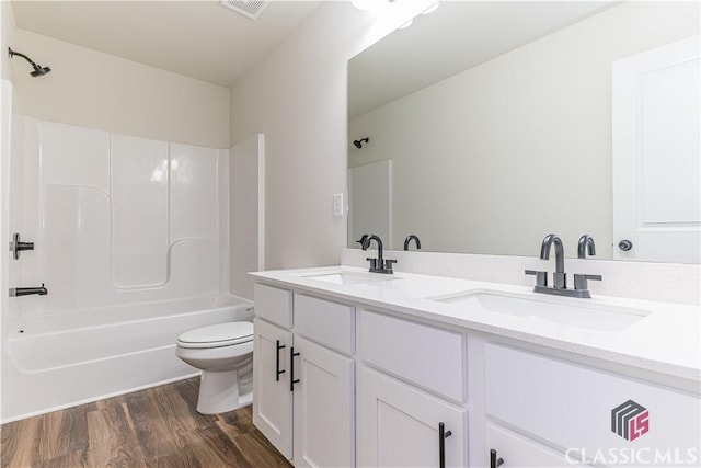 full bathroom featuring shower / bathing tub combination, hardwood / wood-style floors, vanity, and toilet