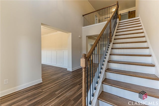 staircase with wood-type flooring and a high ceiling