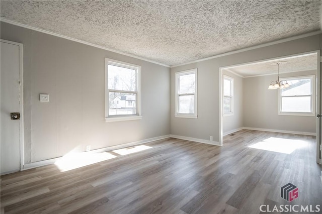 spare room featuring a chandelier, a textured ceiling, hardwood / wood-style flooring, and ornamental molding