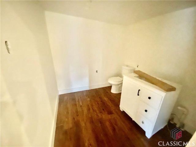 bathroom with toilet, vanity, and wood-type flooring