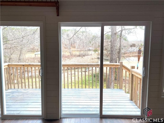 doorway to outside with hardwood / wood-style flooring, wooden walls, and a healthy amount of sunlight