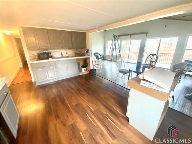 kitchen featuring kitchen peninsula, dark hardwood / wood-style floors, tasteful backsplash, white cabinetry, and sink