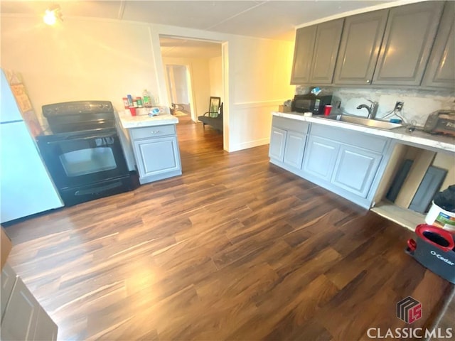 kitchen featuring sink, white fridge, dark hardwood / wood-style floors, black / electric stove, and gray cabinetry