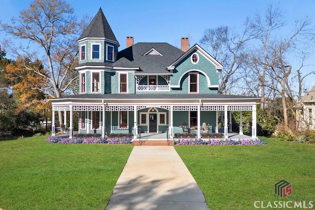 victorian-style house with a chimney, a front lawn, roof with shingles, and a porch