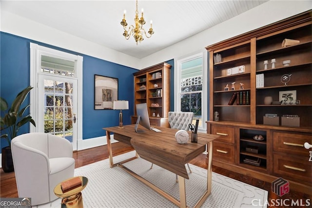 office space with wood finished floors, baseboards, and an inviting chandelier