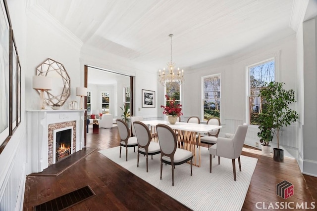 dining room featuring dark wood-type flooring, a chandelier, visible vents, and a premium fireplace