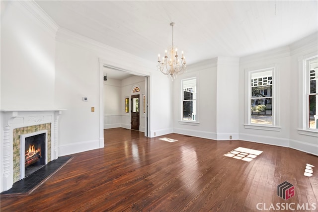 unfurnished living room featuring ornamental molding, wood-type flooring, a wealth of natural light, and a notable chandelier