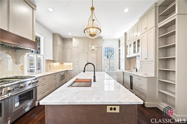 kitchen featuring a sink, an island with sink, stainless steel appliances, dark wood-type flooring, and wine cooler