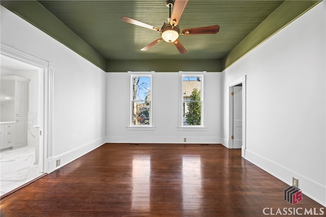 interior space featuring wood finished floors, a ceiling fan, baseboards, and connected bathroom