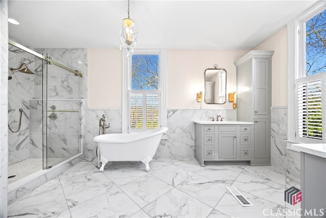 full bathroom with marble finish floor, a wainscoted wall, a marble finish shower, and tile walls