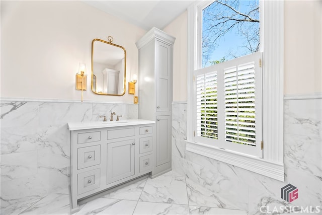 bathroom with wainscoting, tile walls, marble finish floor, and plenty of natural light