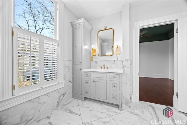 bathroom featuring vanity, marble finish floor, a healthy amount of sunlight, and a wainscoted wall