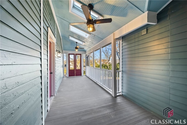 wooden terrace featuring a porch, ceiling fan, and french doors
