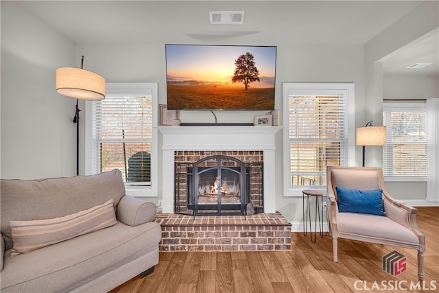 living area with a wealth of natural light, visible vents, and wood finished floors