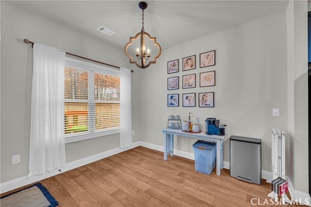 home office with baseboards, light wood-style flooring, visible vents, and an inviting chandelier