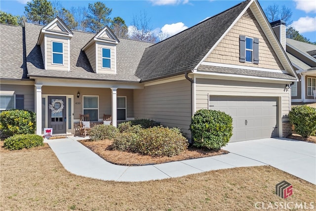 view of front of home featuring a porch, a shingled roof, driveway, and a garage