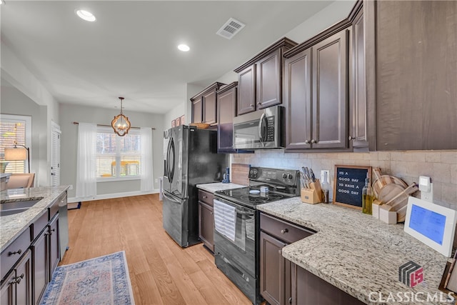 kitchen featuring visible vents, light wood-style flooring, light stone countertops, stainless steel appliances, and backsplash