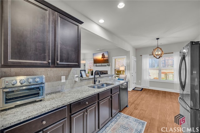 kitchen with dishwashing machine, dark brown cabinets, a sink, and freestanding refrigerator