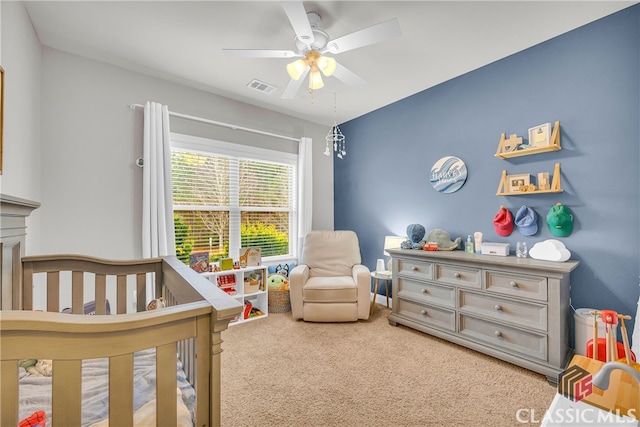 carpeted bedroom featuring a ceiling fan, a nursery area, and visible vents