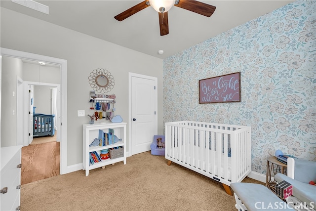 carpeted bedroom with baseboards, a crib, visible vents, and wallpapered walls