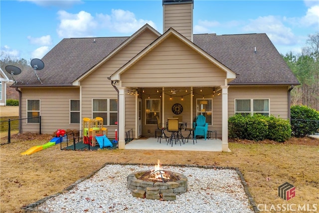 rear view of property with an outdoor fire pit, fence, roof with shingles, and a patio