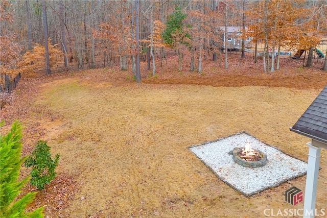 view of yard with an outdoor fire pit, playground community, and fence