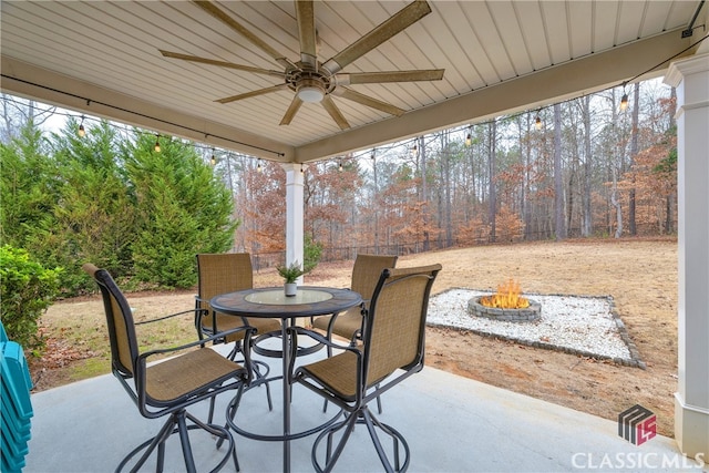 view of patio / terrace with a fire pit, outdoor dining area, a fenced backyard, and a ceiling fan