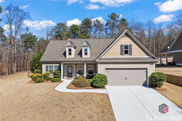 view of front of home with a garage, concrete driveway, roof with shingles, and a front lawn