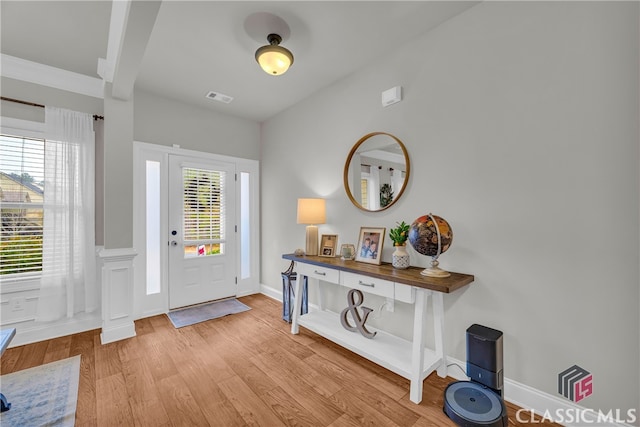 foyer entrance featuring a healthy amount of sunlight, light wood-style flooring, visible vents, and baseboards