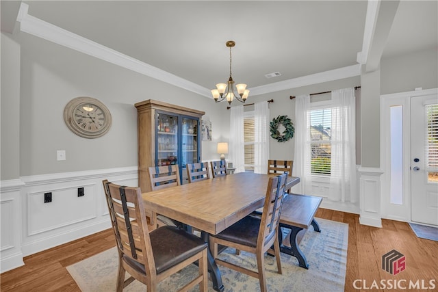 dining space with visible vents, a chandelier, wood finished floors, and ornamental molding