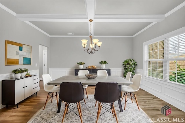 dining space with coffered ceiling, light hardwood / wood-style flooring, ornamental molding, beamed ceiling, and a chandelier