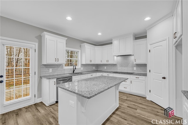 kitchen featuring a center island, light stone countertops, white cabinetry, and sink