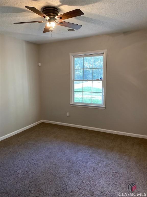 carpeted empty room featuring ceiling fan and a textured ceiling