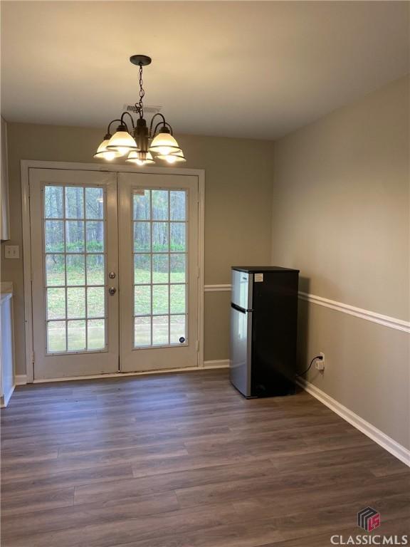 entryway with french doors, a healthy amount of sunlight, dark hardwood / wood-style floors, and a notable chandelier