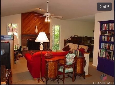 living room featuring wooden walls, ceiling fan, lofted ceiling, and a brick fireplace