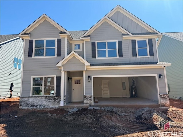 view of front facade featuring a garage, driveway, roof with shingles, board and batten siding, and brick siding