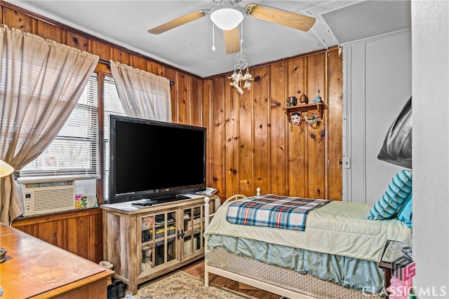 bedroom with ceiling fan, cooling unit, wood-type flooring, and wood walls