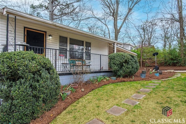 doorway to property with a porch and a yard