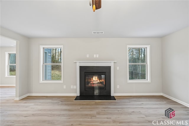 unfurnished living room featuring a healthy amount of sunlight, ceiling fan, and light hardwood / wood-style floors