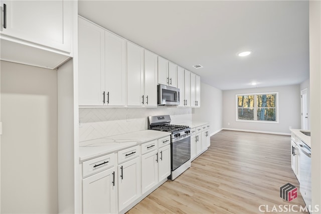 kitchen featuring white cabinets, appliances with stainless steel finishes, and backsplash