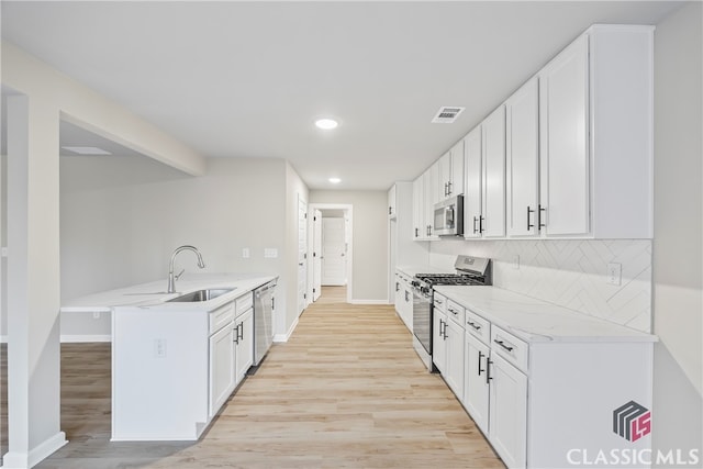 kitchen with kitchen peninsula, decorative backsplash, white cabinets, and stainless steel appliances