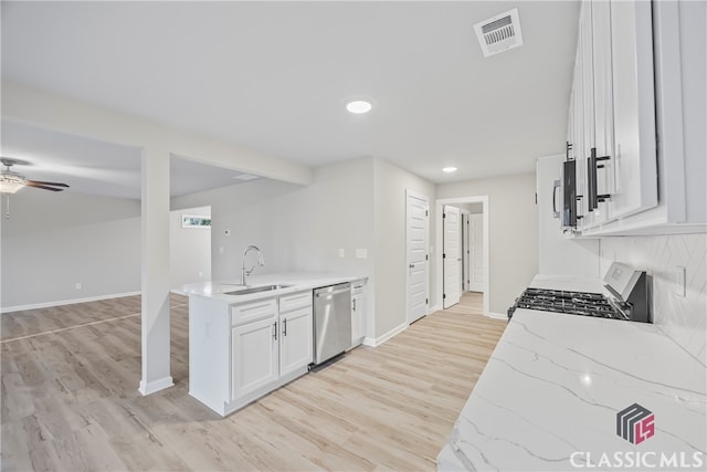 kitchen featuring light stone countertops, sink, stainless steel appliances, white cabinets, and light wood-type flooring