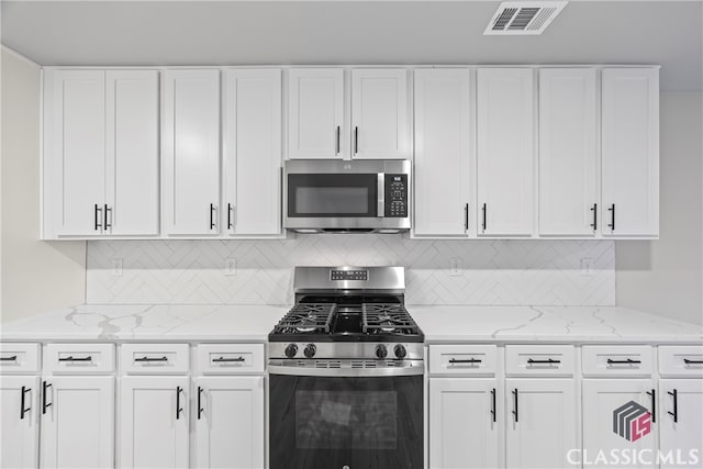 kitchen featuring light stone counters, white cabinetry, appliances with stainless steel finishes, and tasteful backsplash