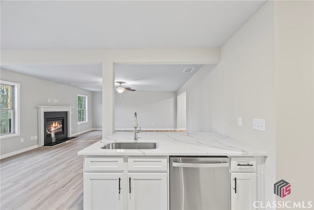 kitchen featuring dishwasher, white cabinets, light stone countertops, and sink